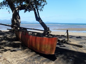 Musicale plage à marée basse avec en premier plan une pirogue à balancier traditionnelle (laka)